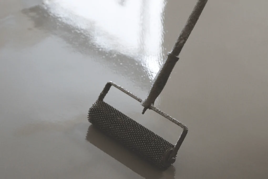 A spike roller being used over smoothing compound